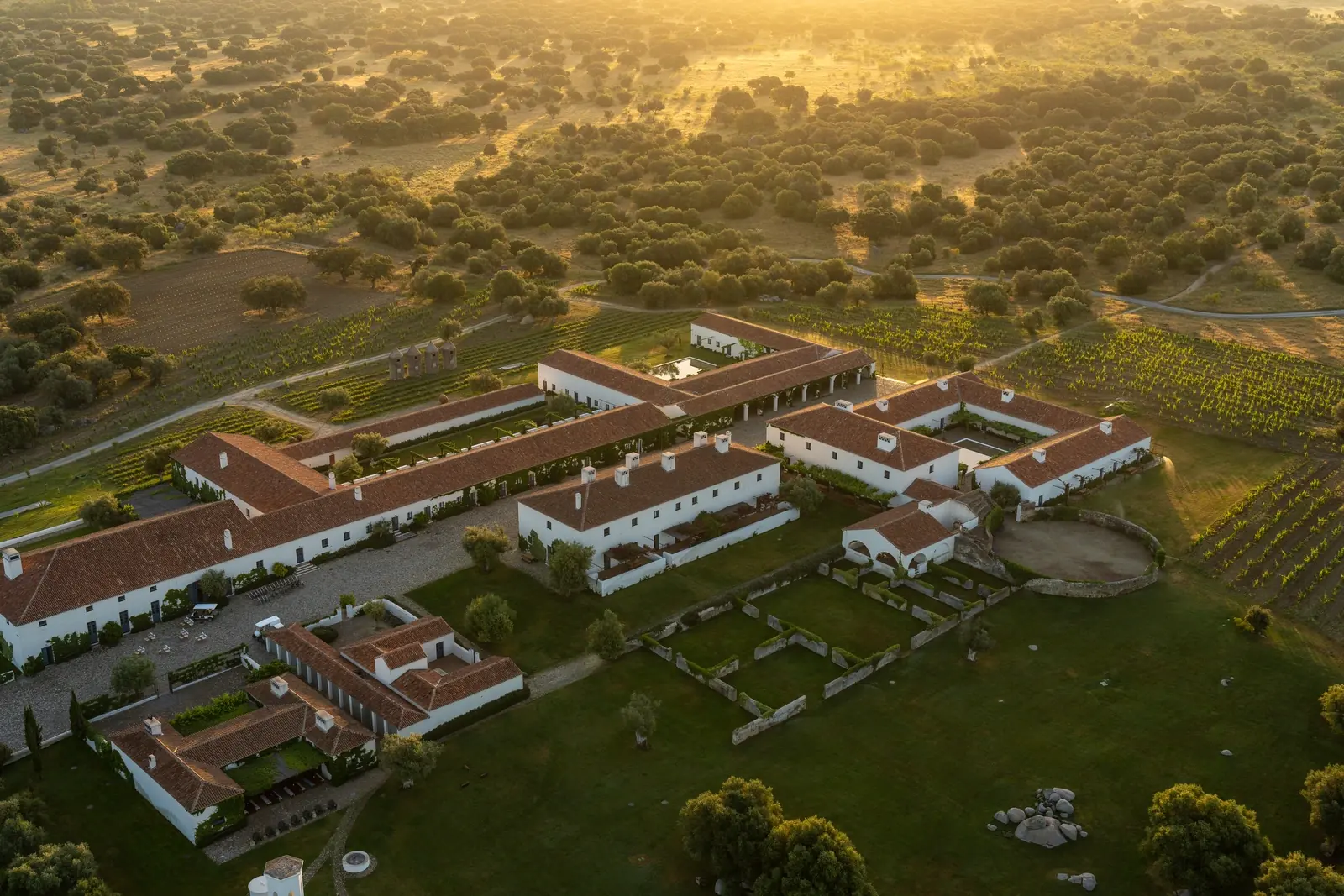 São Lourenço do Barrocal · dusk aerial of the 780-hectare working-farm estate in Monsaraz, Alentejo, with the medieval castle on the distant ridge