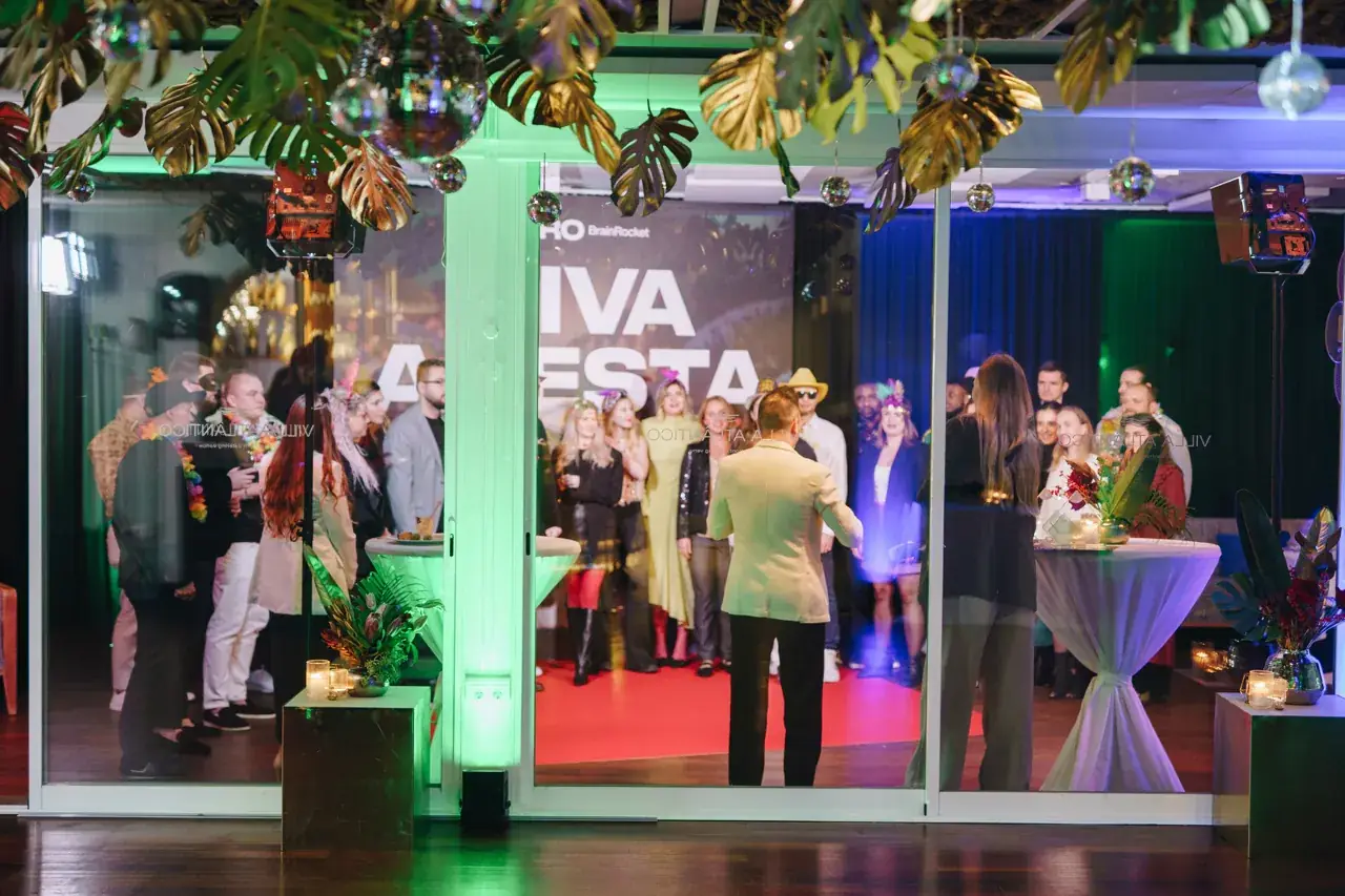 Sala de uma festa de Natal de empresa com convidados junto ao palco «Viva a Festa»