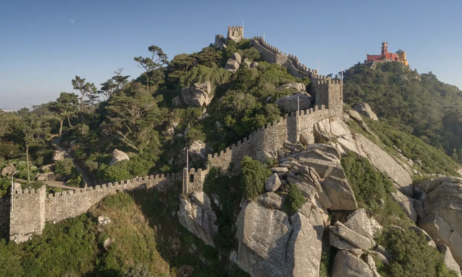 Parques de Sintra, showing Moorish Castle medieval ramparts with Pena Palace on the Sintra hills, both UNESCO World Heritage monuments under one governance body.