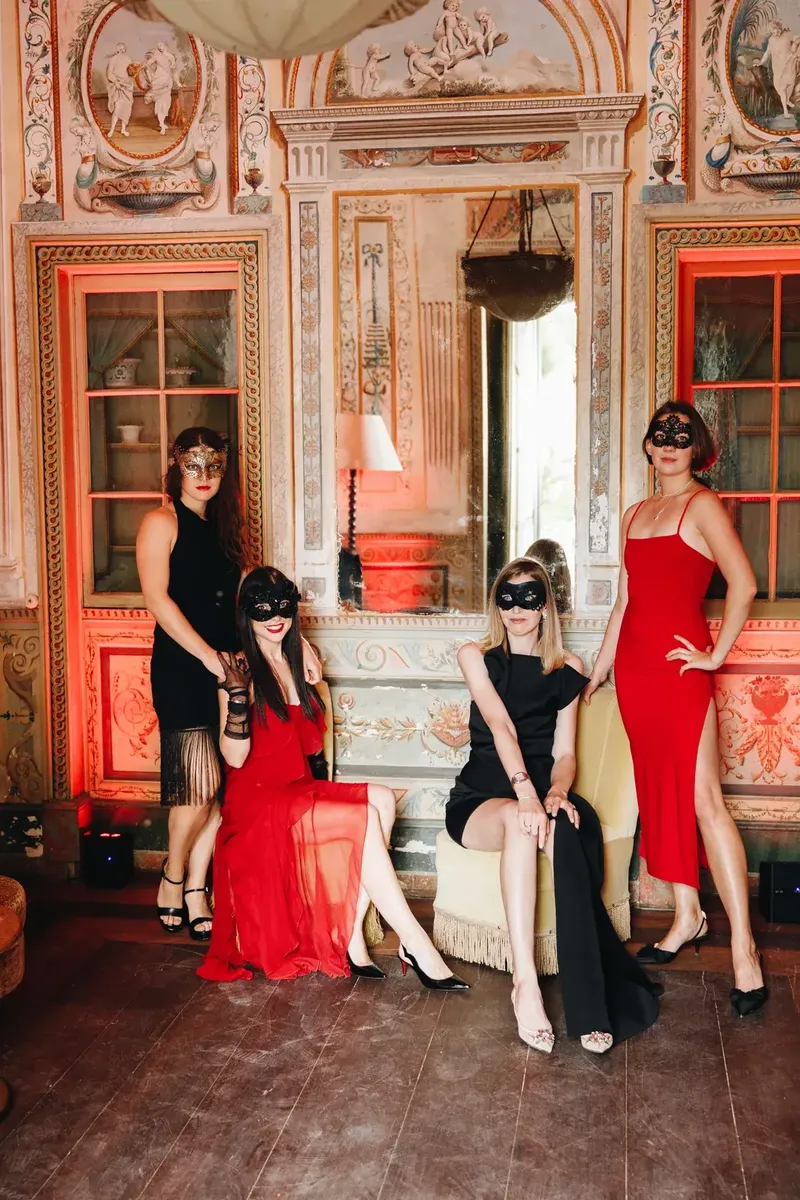 Convidados com máscaras de baile e traje black tie num salão com frescos do Palácio do Grilo