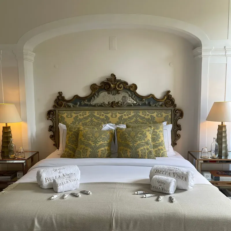 Suite na Quinta da Bella Vista com cabeceira antiga entalhada e luz de jardim