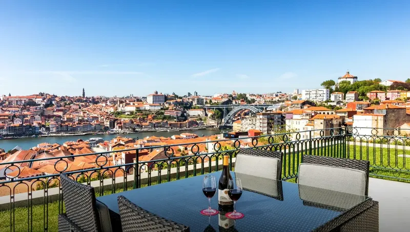The Yeatman terrace dining table set for an intimate seated dinner with the Luiz I Bridge framing the Douro behind, used by BTQ Events as an alfresco format for senior-tier private dinners and press-launch evenings